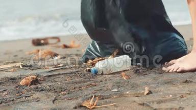 特写志愿者拿起塑料瓶在黑色沙滩上放入黑色塑料袋.. 志愿者打扫卫生
